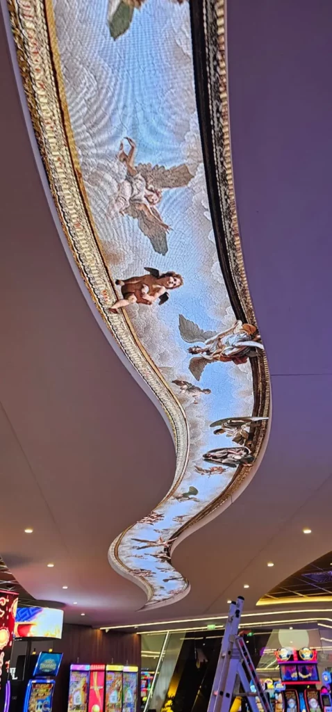 Écran LED courbe encastré dans un plafond de casino, diffusant une fresque d'anges